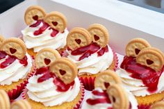 cupcakes with heart shaped cookies and cream frosting in a white box on a table