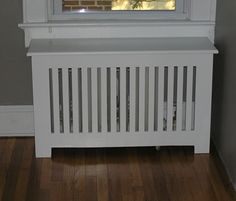 a white radiator sitting on top of a wooden floor next to a window