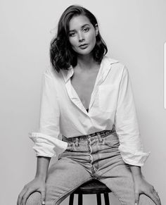 a black and white photo of a woman sitting on a stool