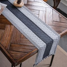 a wooden table topped with a gray and black striped table runner