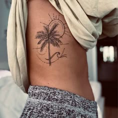 a woman's stomach with a palm tree tattoo on her left side ribcage