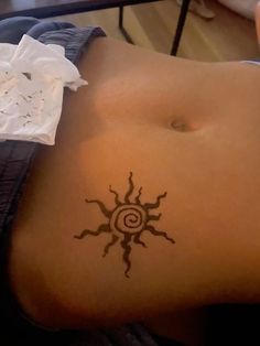 a woman's stomach with a tattoo on her side and the sun in the middle