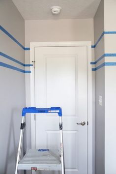 a step ladder in front of a white door with blue tape on the wall behind it