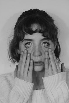 a black and white photo of a woman covering her eyes