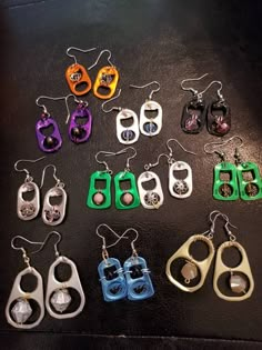 six pairs of earrings with different colors and designs on them, sitting on a table