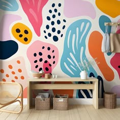 a room with colorful wallpaper and wooden table in front of the wall, next to two wicker baskets