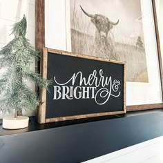 a wooden sign sitting on top of a mantle next to a potted pine tree