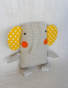 an elephant stuffed animal sitting on top of a white couch next to a pillow with polka dots