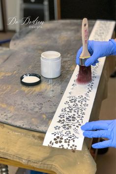 a person in blue gloves is painting on a table