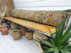 a bench with potted plants and vases next to it