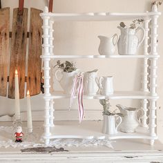 a shelf filled with white dishes and candles