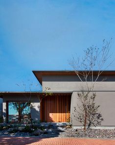 a modern house with brick walkway and trees