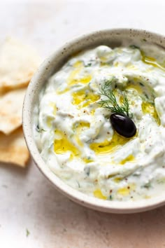 a bowl of dip with olives and pita chips