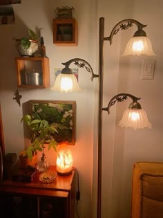 three lights that are on the side of a wall next to a table with a potted plant