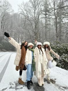 three women standing in the snow with their arms out and one holding her hand up