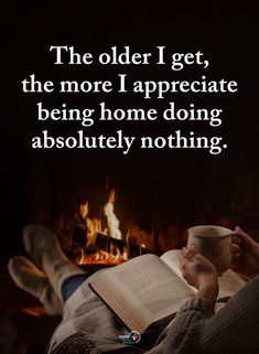 someone is reading a book and holding a cup in front of a fireplace with the caption, the older i get, the more i appreciateate being home doing absolutely nothing