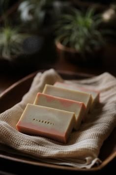 three bars of soap sitting on top of a wooden tray next to a potted plant