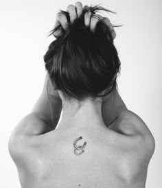 the back of a woman's neck with a horseshoe tattoo