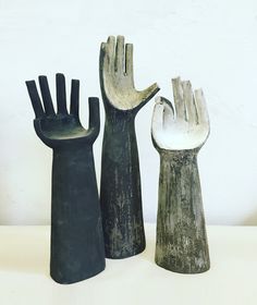 three black and white ceramic hand sculptures sitting on top of a table next to each other