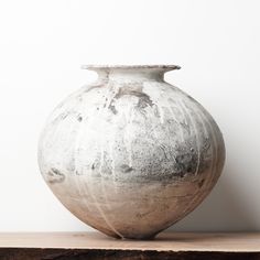 a white vase sitting on top of a wooden table