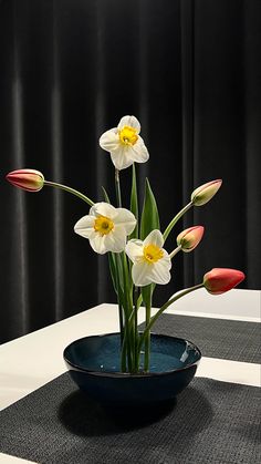 a blue bowl with flowers in it on a black and white tableclothed place mat