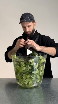 a man standing in front of a large glass bowl filled with green leaves and plants