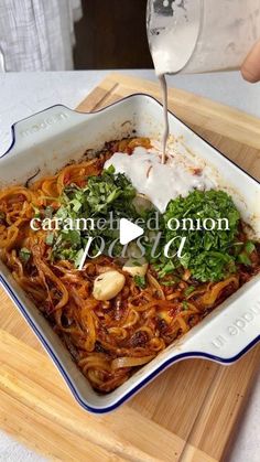 someone is pouring water into a dish with noodles and vegetables