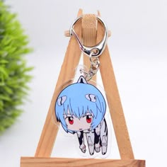 a key chain with an anime character on it sitting on a wooden stand next to a potted plant