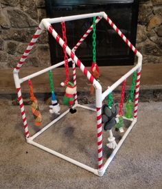 a christmas decoration made out of plastic tubes and candy canes on the floor in front of a fireplace