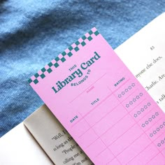 a pink library card sitting on top of an open book