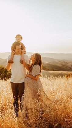 a man and woman holding a child in a field