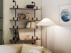 a living room filled with furniture and a lamp on top of a wooden shelf next to a white wall