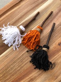 three tassels on a cutting board, one is orange and the other is black