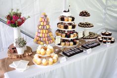 a table topped with lots of cupcakes and cakes next to a vase filled with flowers