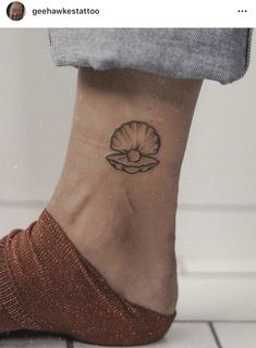 a woman's foot with a small shell tattoo on her left side ribcage