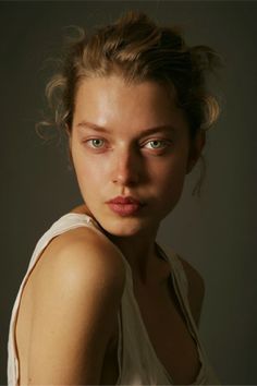 a woman is posing for a photo with her hair blowing in the wind and blue eyes