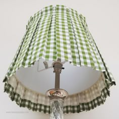 a green and white checkered lamp shade hanging from a ceiling fixture in a room