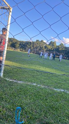 a group of people playing soccer on a field behind a fence with the net in front of them