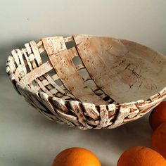 a wooden bowl sitting on top of a table next to oranges