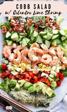 cobb salad with shrimp, cucumber, tomatoes and lettuce on a white plate