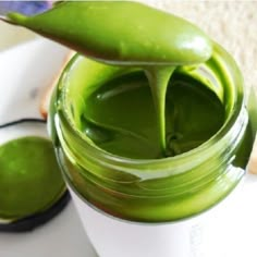 a jar filled with green liquid sitting on top of a white plate next to a slice of bread