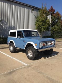 an old blue and white truck parked in a parking lot next to a metal building