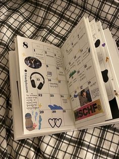 an open book with stickers on it sitting on top of a plaid cloth covered bed