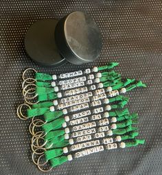 several green and white key chains sitting on top of a table next to some metal containers