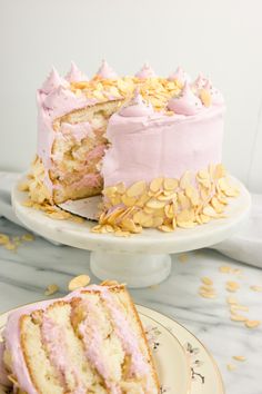 there is a cake with pink frosting and almonds on the plate next to it