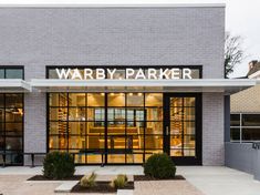 the front entrance to a store with glass doors and windows on both sides that read, warby parker