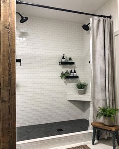 a white tiled shower with black accents and shelves on the wall next to a wooden bench