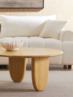 a living room with a couch, coffee table and pillows on the floor in front of it