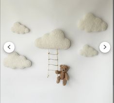 there is a teddy bear hanging on the wall next to some clouds and a ladder