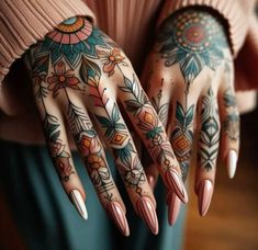 a woman's hands with tattoos on them and flowers painted on their fingers,